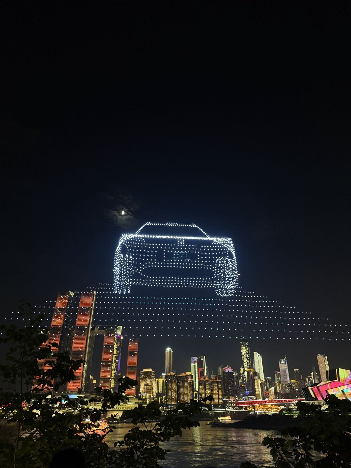 A car drawn by drones in the night sky over the Chongqing skyline