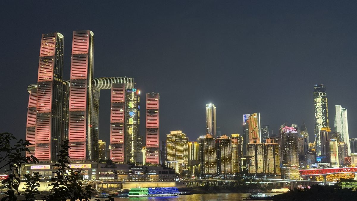 Raffles City Chongqing lit pink at night with The Crystal skybridge across its towers