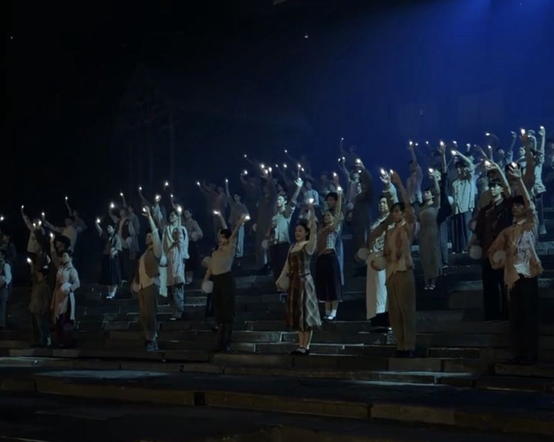The cast holding up candles on the stairs in the finale of Chongqing 1949