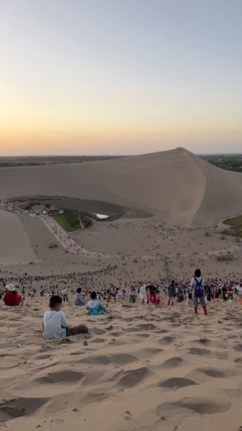 Crowds sitting on the Mingsha Shan dunes waiting for sunset over Crescent Lake