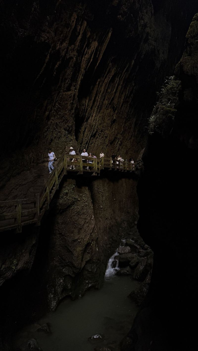 Visitors on a wooden walkway along the dark cliff of Longshuixia fissure gorge