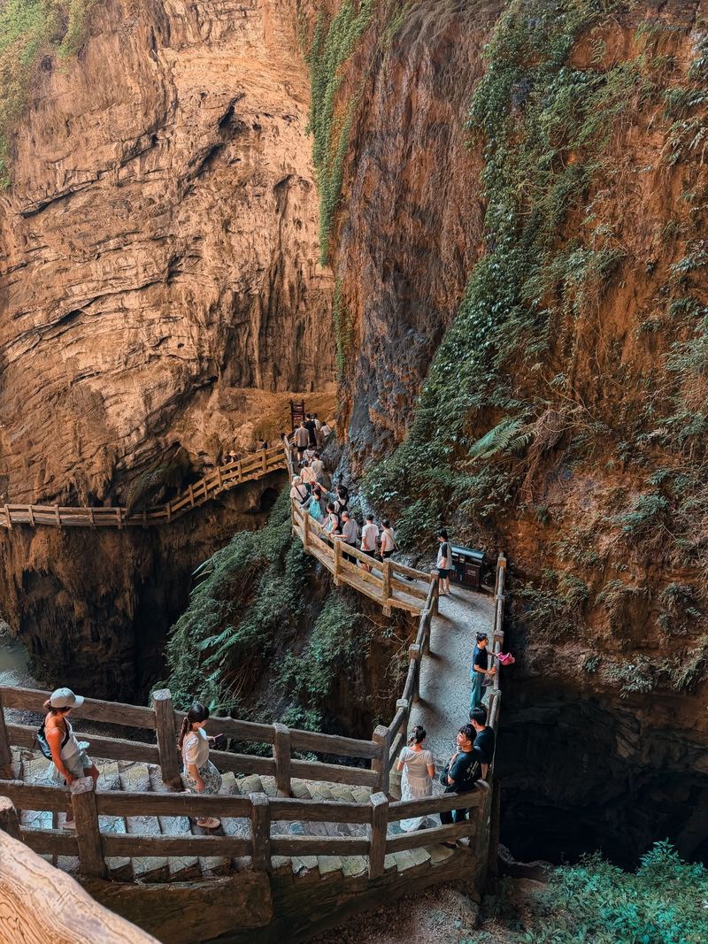 Visitors on stone walkways along the orange cliffs of Longshuixia gorge