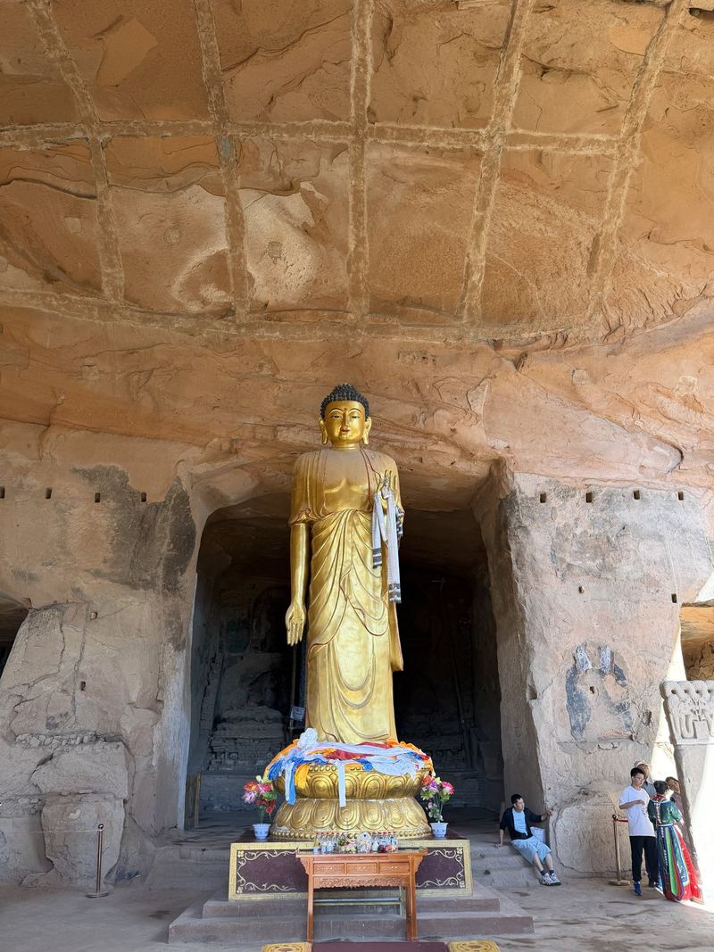 A golden standing Buddha in a cave at Mati Temple