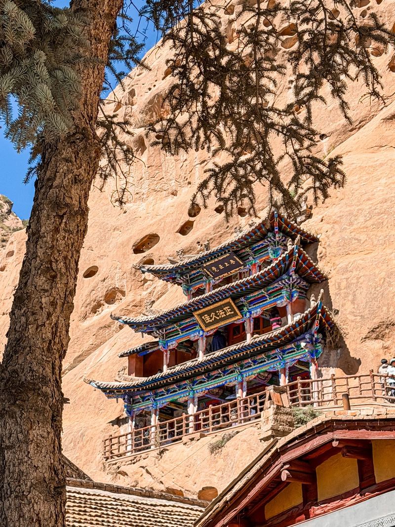 A painted three storey pavilion against the sandstone cliff at Mati Temple