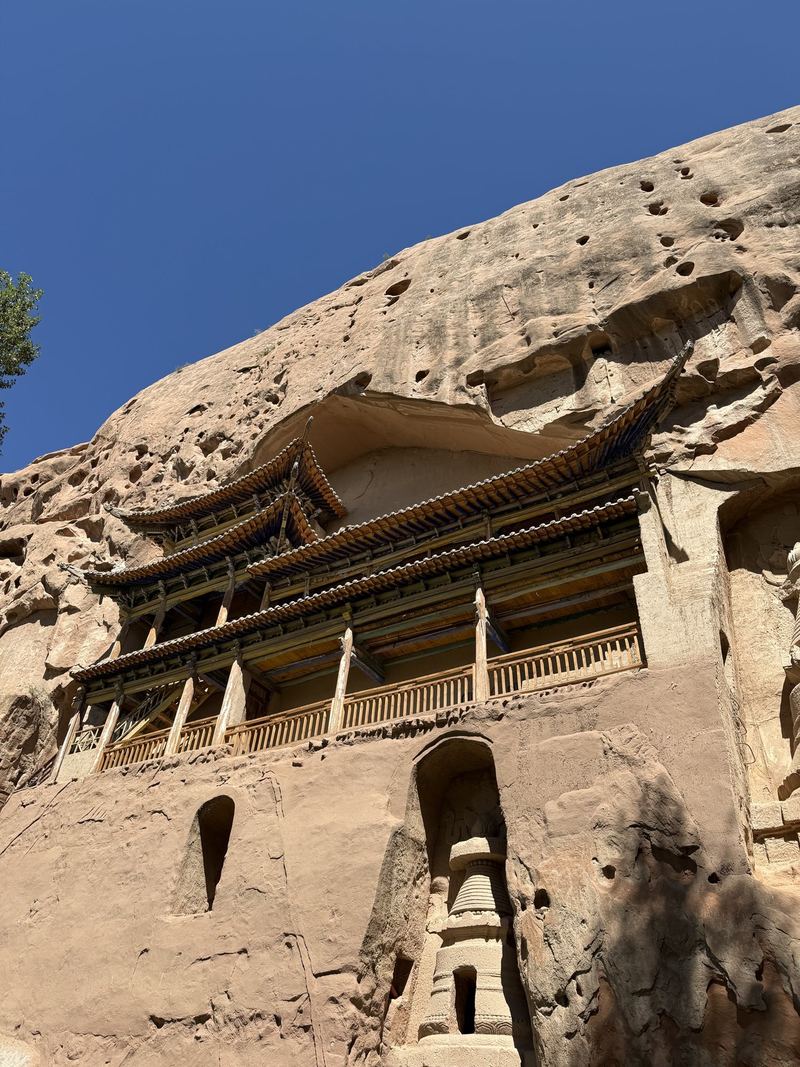 A wooden gallery and a carved stupa niche in the Mati Temple cliff