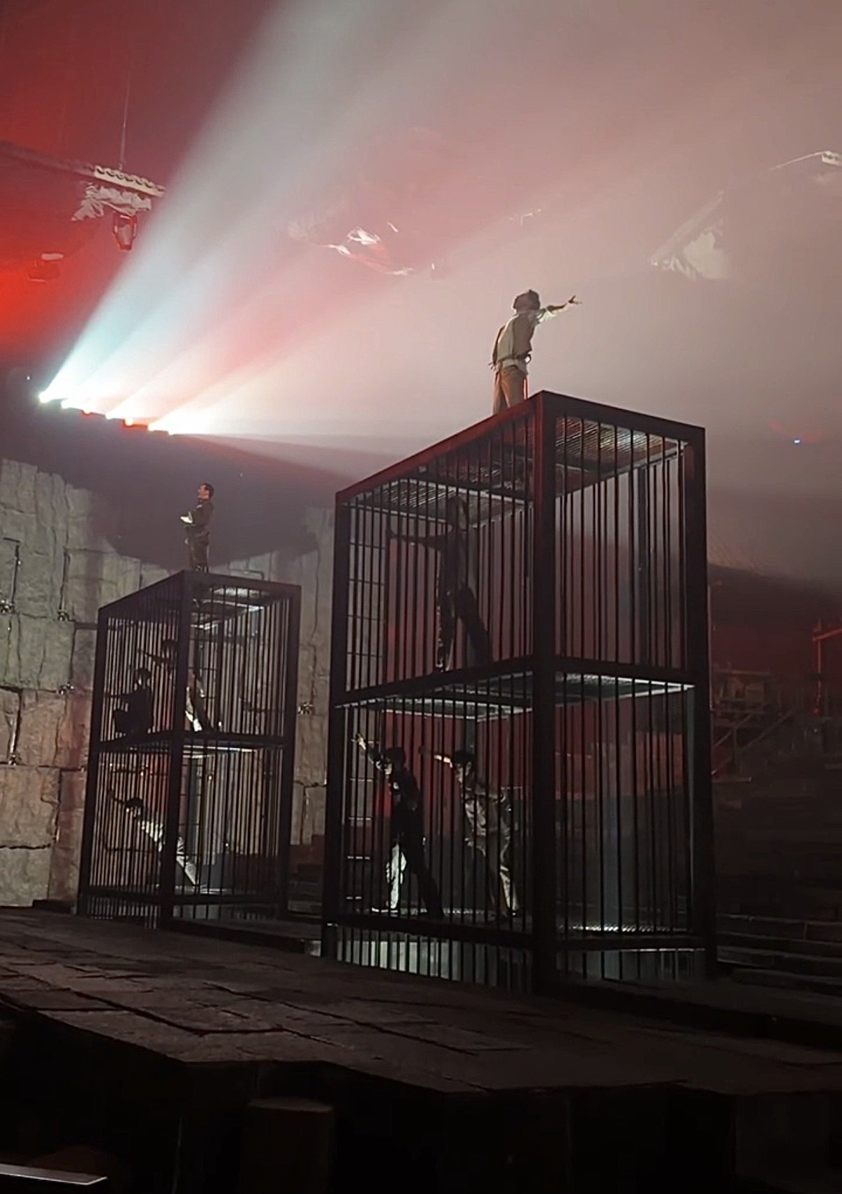 Performers in tall cages under red light in the Chongqing 1949 show