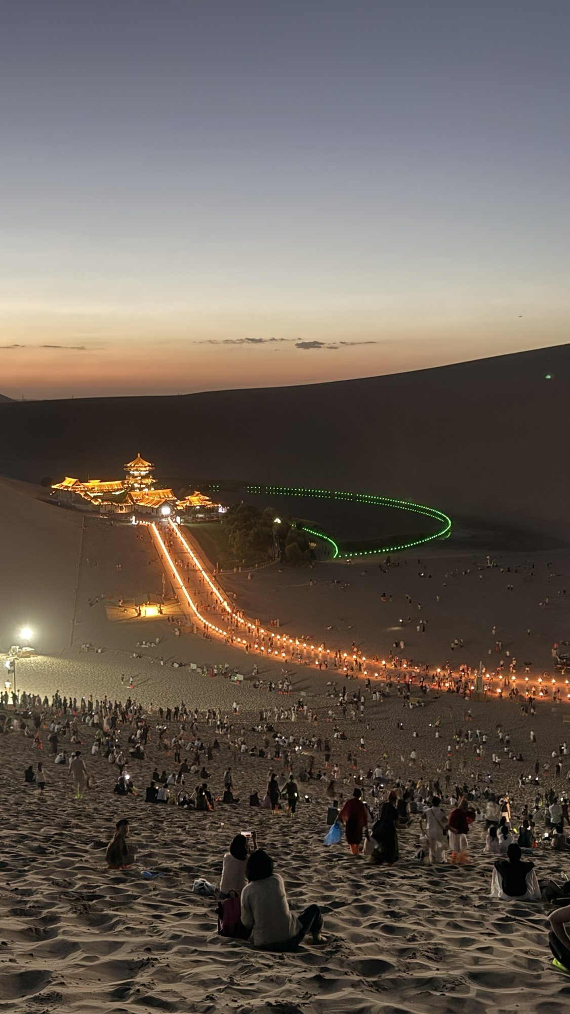 Crescent Lake lit up at night, seen from the top of the Mingsha Shan dunes